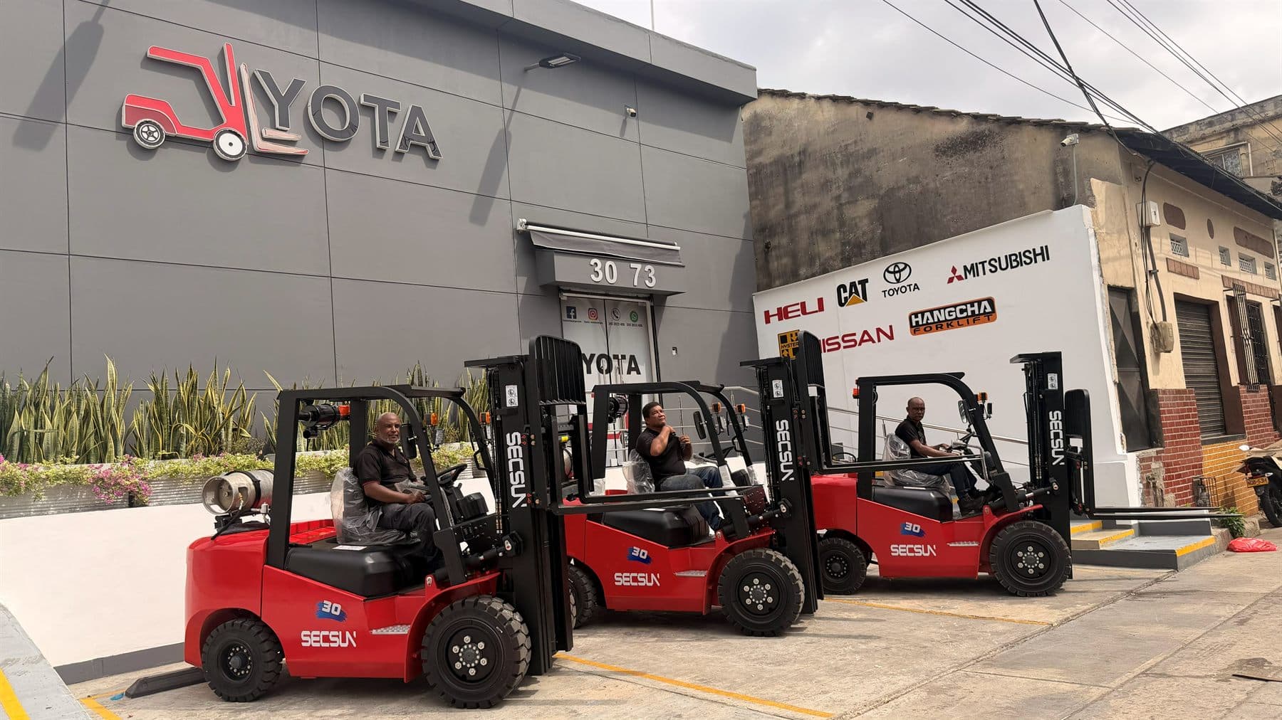 Tres montacargas Secsun FG30 rojos, nuevos, frente a la bodega de YOTA Montacargas en Barranquilla